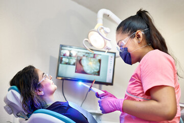 Dentist preparing for a tooth whitening procedure with a female client