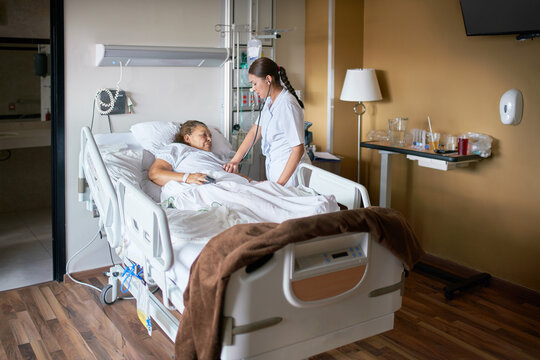 Photo of private hospital room with medical practitioner and patient in bed