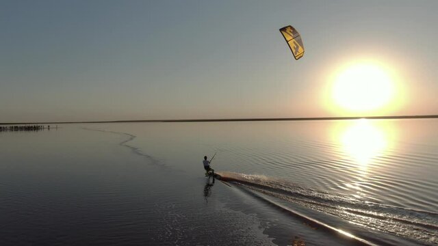 Aerial footage of a man kitesurfing on pink water of the lake, nature and sports