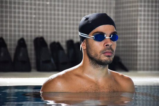 Sporty fit man in swimming goggles in pool.