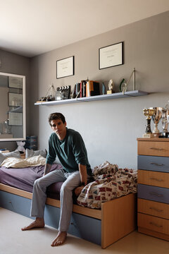 Young athlete sitting on bed in morning