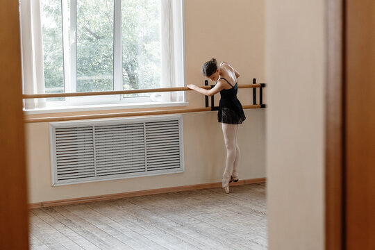 Young ballerina tiptoeing near window