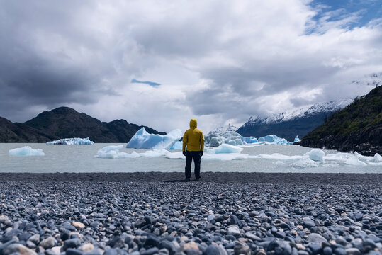 Hiker with a yellow jacket surrounded by some ice floes in Grey Lake, Patagonia, Chile