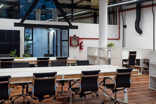 Chairs lined up at table in empty coworking space