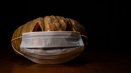 A closeup shot of a Halloween pumpkin with sanitary mask - concept of the new normal