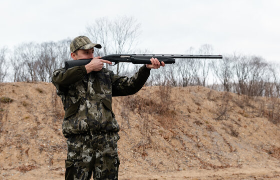 Male hunter shooting near hill
