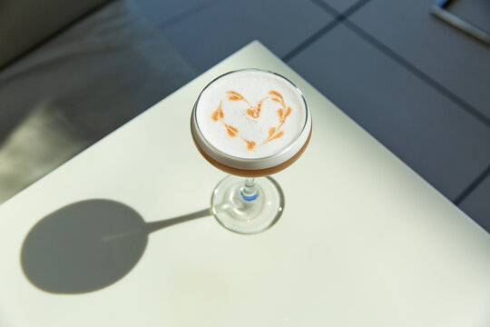 Coffee Cocktail in Champagne Coup in White Bar with Heart Design in Foam with Shadow