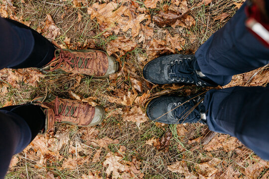 Two people looking down on their shoes among colorful autumn leaves