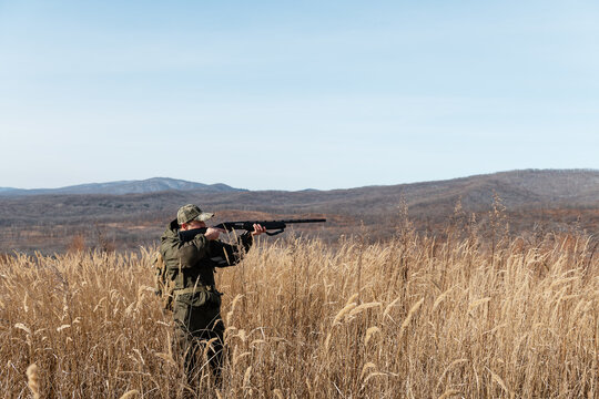Man hunting in field near mountains