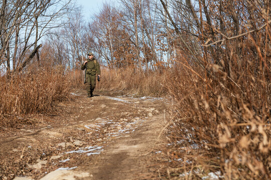 Hunter walking on countryside road on autumn day
