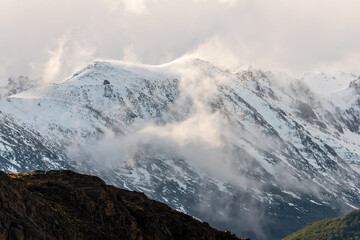 Wind blowing snow over mountain peaks