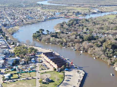 Foto a&eacute;rea de un pueblo con costa al r&iacute;o. A la izquierda est&aacute; la ciudad y a la derecha los parques p&uacute;blicos. 