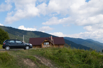 Fototapeta na wymiar Black car staying near the cottage in mountains