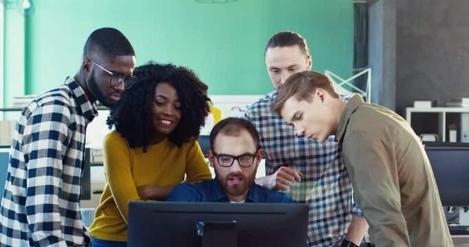 Multinational team of young professionals: four men and one woman, discussing project in modern office. Brainstorming managers.