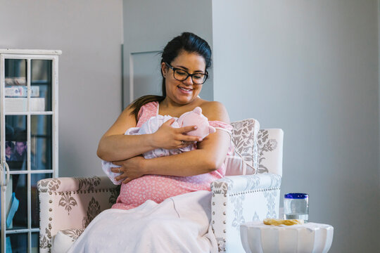 Pregnant Hispanic Mother Breastfeeding and Connecting with Newborn Baby at Home