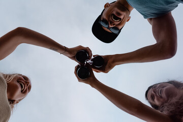 Delighted young people clinking bottles of beer