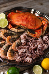 Close-up of big round dish with king crab, shrimps and octopuses served with lime. Seafood concept. Healthy meal. Traditional Thai recipe.