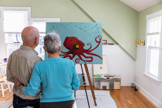 Senior Man Painting in Home Artist Studio with Happy Wife at His Side