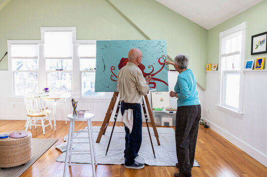 Senior Man Painting in Home Artist Studio with Wife at His Side