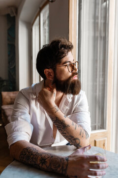 Thoughtful hipster with cocktail in cafe