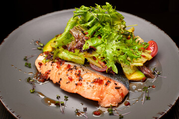 Salad with avocado and salmon, on a black background