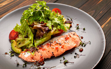 Salad with avocado and salmon, on a wooden background
