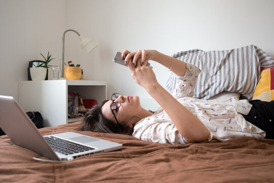 Portrait of a young female model laying on the bed and using laptop