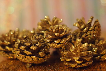 Golden pine cones in a blurry red white and green christmas background Xmas decoration