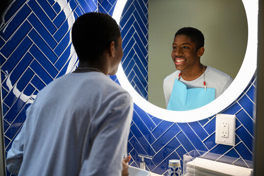 Young African American Boy Looking in Mirror at new Invisible Dental Retainer