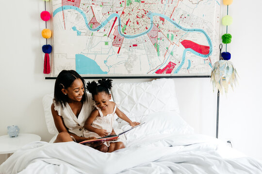 A mother reading to her daughter in a colorful bedroom.