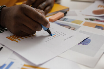 Crop black man highlighting data on paper