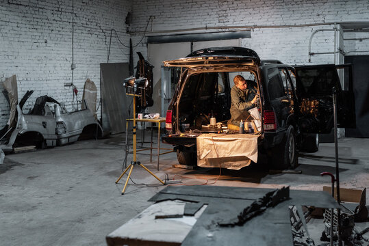 Mechanic repairing car in dark garage