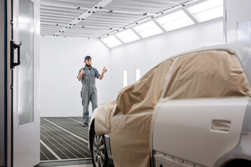 Male mechanic gesturing for car driver in garage