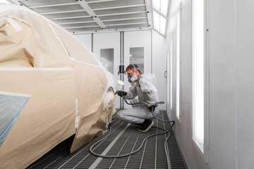 Male worker painting car side wing