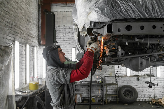 Male mechanic fixing vehicle in workshop