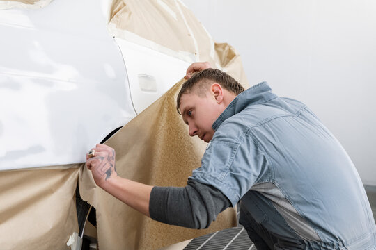 Male technician covering car wheel with paper