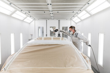 Technician spraying paint on top of car