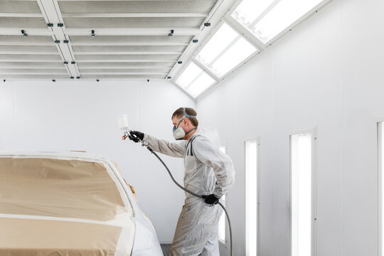 Male mechanic painting car in garage