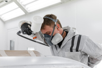 Mechanic spraying car roof with paint