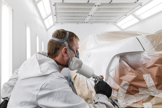 Male mechanic painting tail of car