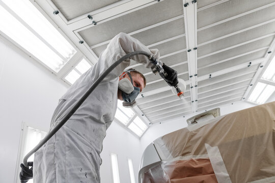 Technician painting spoiler of vehicle