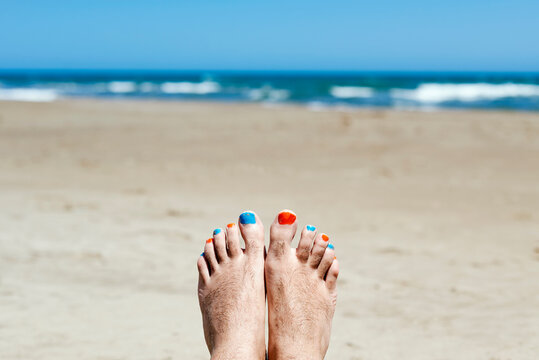man with painted toenails on the beach