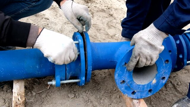 Workers installing water supply pipeline system, close up