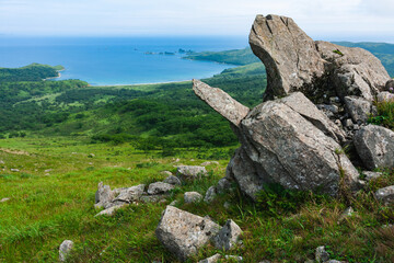 Fototapeta na wymiar Large rocks on top of the hill, summer sea background.