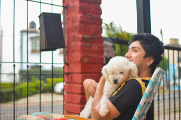 young man hugging smiling his poodle dog