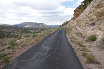 Asphalt highway going through desert environment and rocky cliff