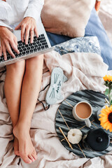 Woman is enjoying coffee in the bed. Working on the laptop. Sunflower arrangement. Bedroom vibe. Autumn season. Feeling home comfortable. Enjoying little things. Fall colors and mood. Work at home.