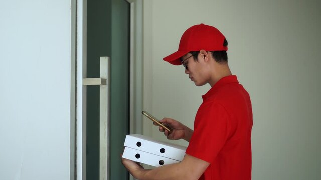 shot of young asian postal worker man carrying pizza boxes and waiting to send to customer in front of home for modern lifestyle and e-commerce delivery business concept
