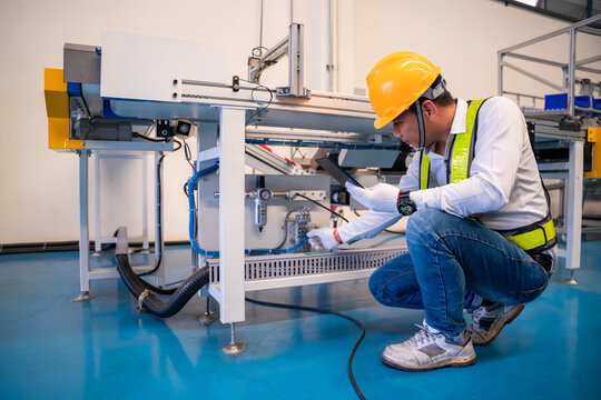 Asian man Mechanic technician worker working install and checking the electric control cabinet of conveyer in industrial factory.