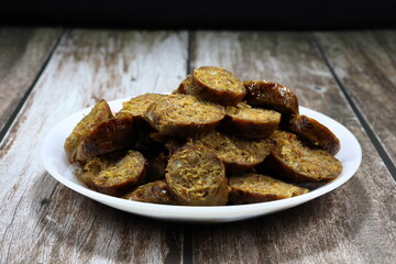 Pile of sliced spicy pork sausage marinated with spices herbal vegetable in Thai style on the plate. Famous appetizer menu in local Asia restaurant. 